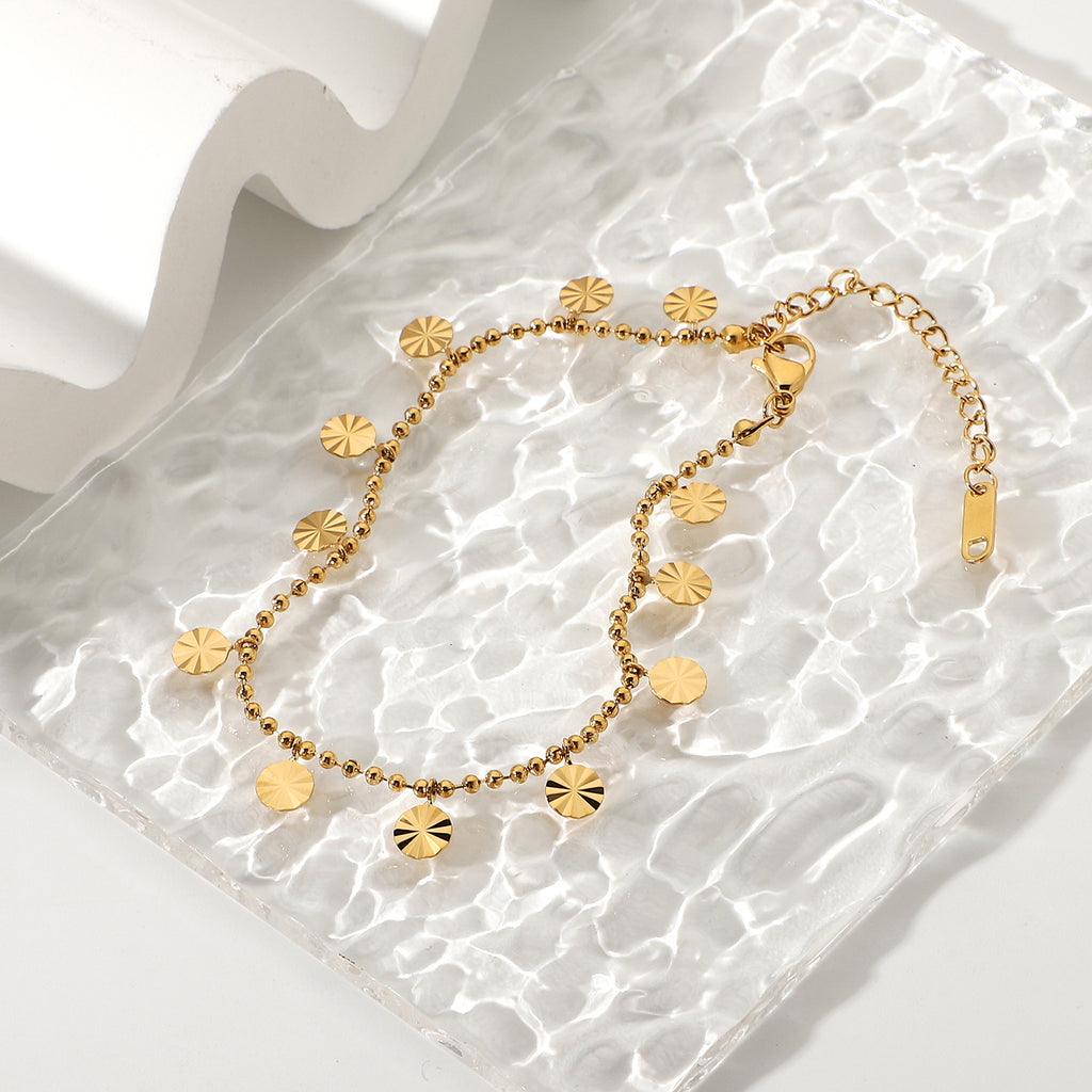Gold plated disc charm anklet on rippled clear display
