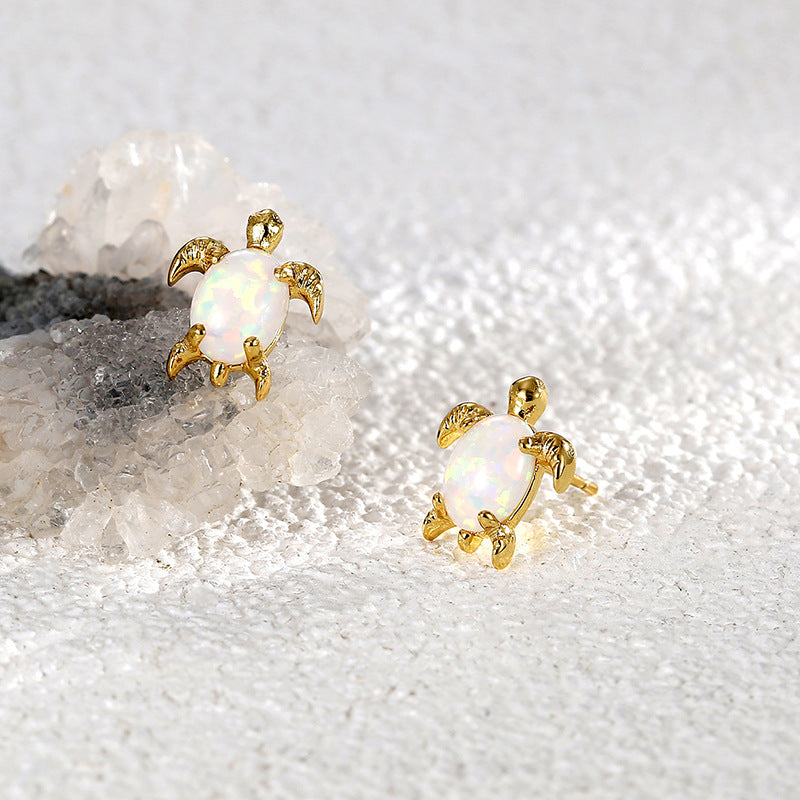 Gold plated opal sea turtle stud earrings styled on stone