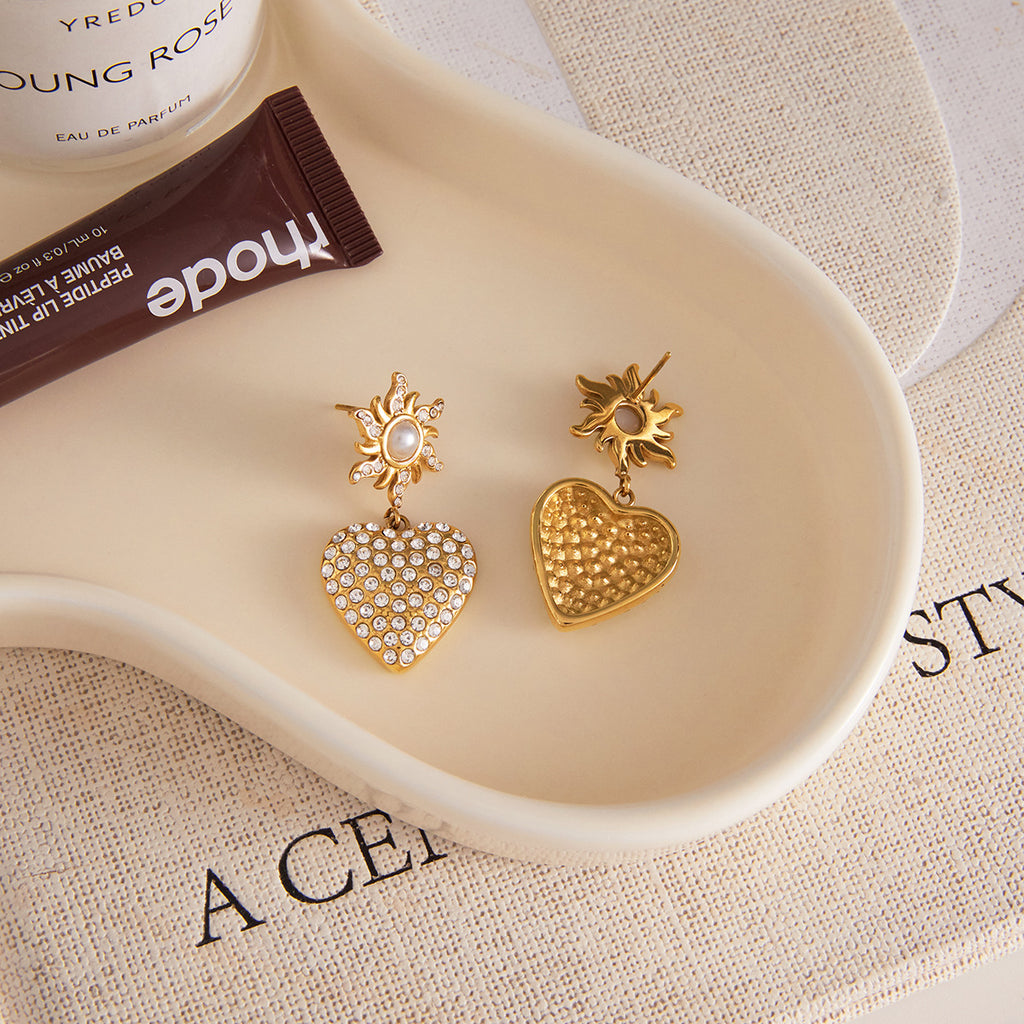 Close-up of sunburst stud and clear stone heart earrings