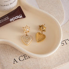 Close-up of sunburst stud and clear stone heart earrings