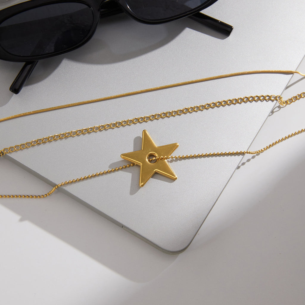 Gold tone chains and star pendant laid on a board
