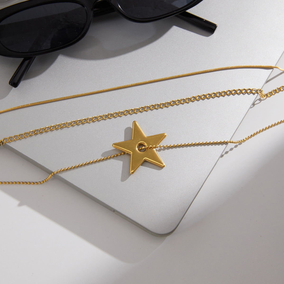 Gold tone chains and star pendant laid on a board