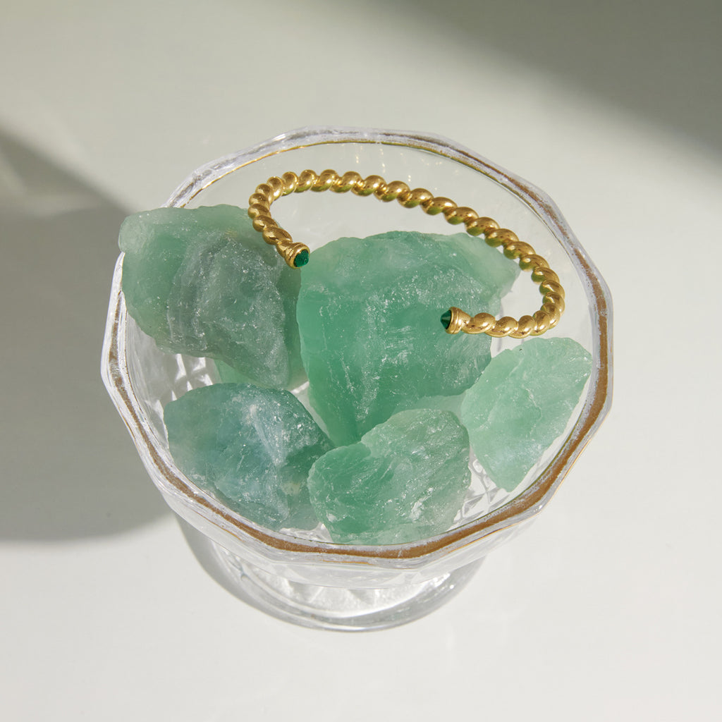 Twisted open cuff resting on a green crystal display