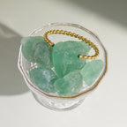 Twisted open cuff resting on a green crystal display