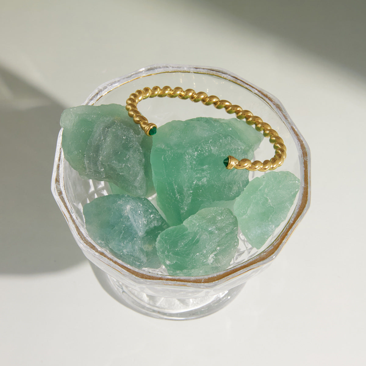 Twisted open cuff resting on a green crystal display