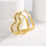 pair of gold plated coiled heart hoop earrings standing upright