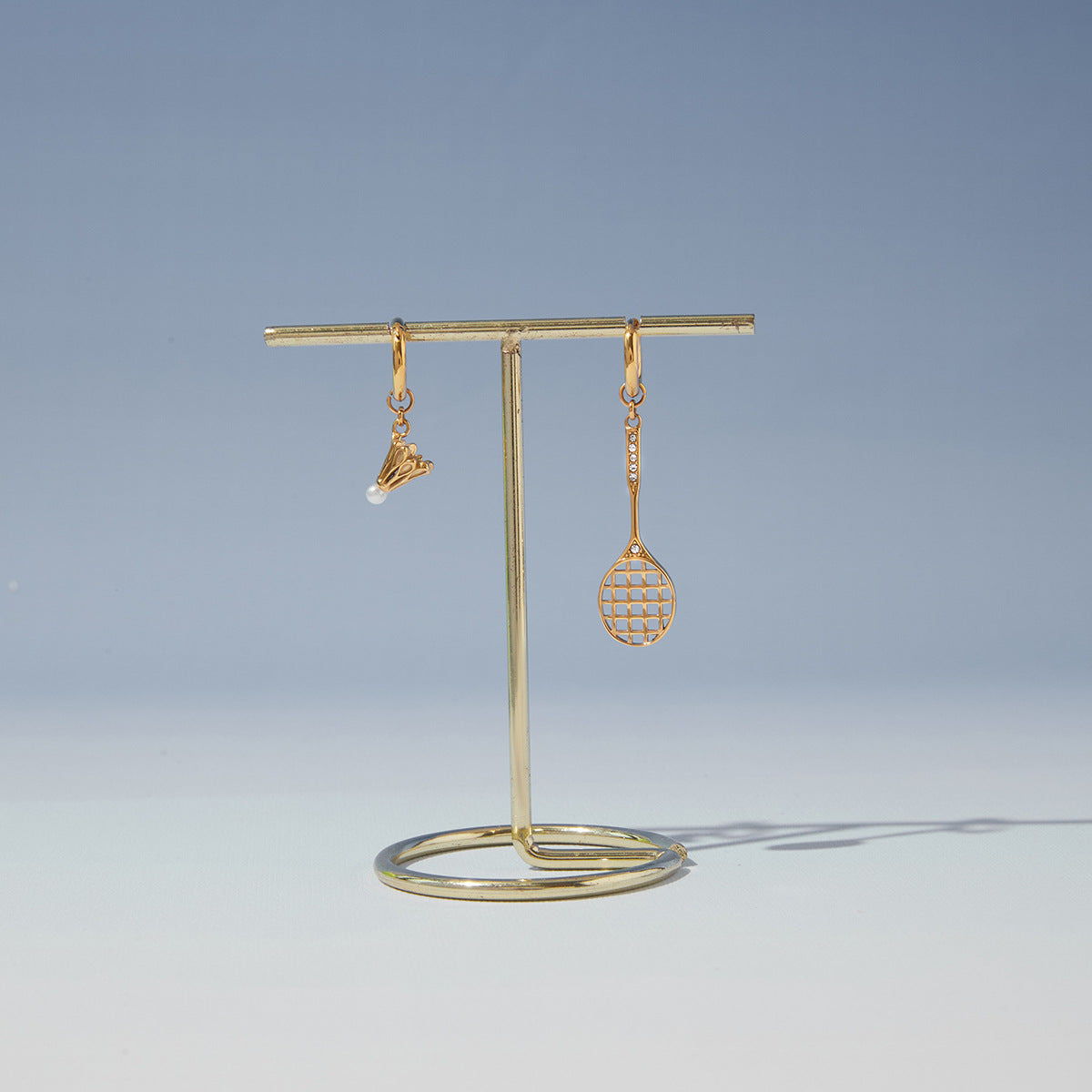 Racket and shuttlecock earrings hanging on a stand