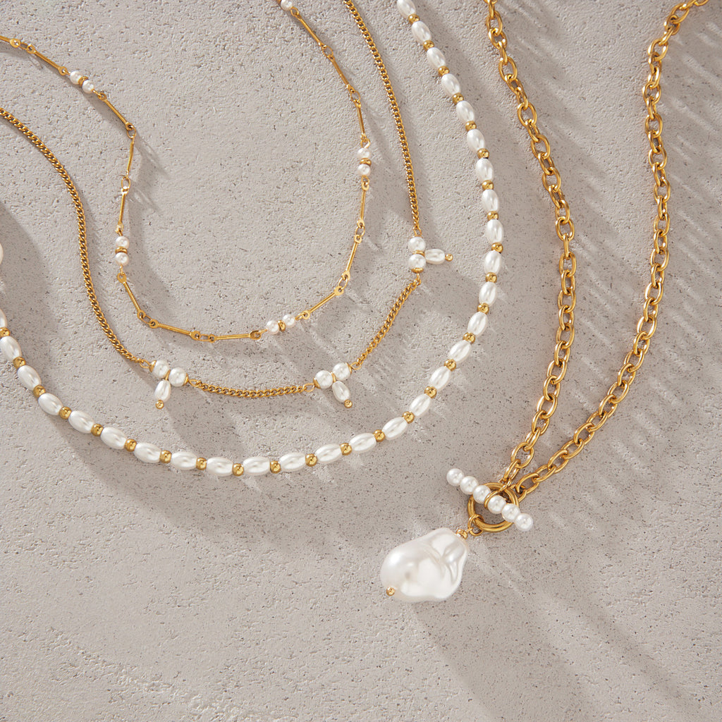 Imitation pearl strand and three chain necklaces on white