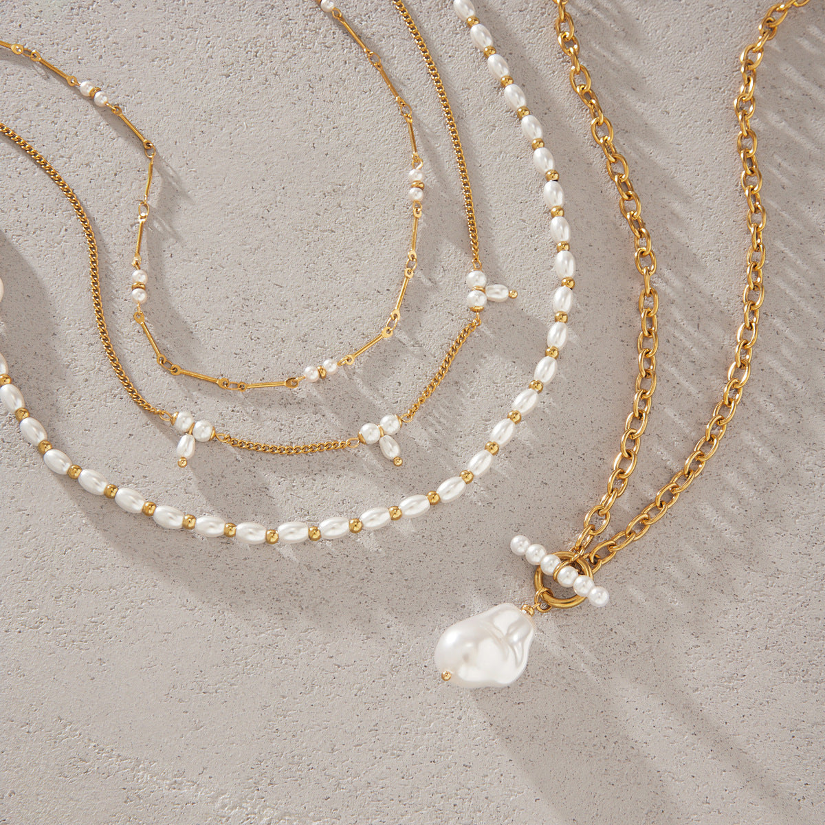 Imitation pearl strand and three chain necklaces on white