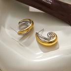 Overlapping gold and silver tone curves with stud posts
