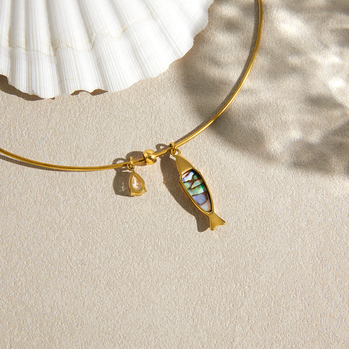 multicolor inlay fish pendant beside a shell