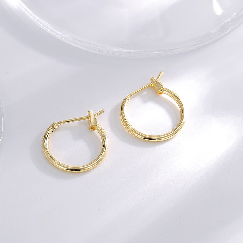gold plated round hoop earrings arranged on a clear surface