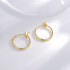 gold plated round hoop earrings arranged on a clear surface
