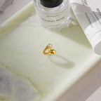 Gold tone sculptural ring resting on a tray