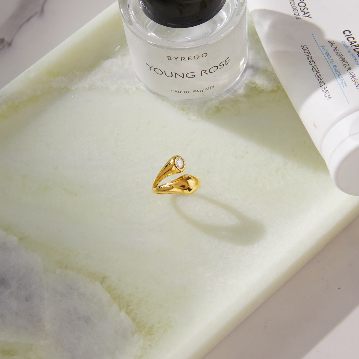 Gold tone sculptural ring resting on a tray