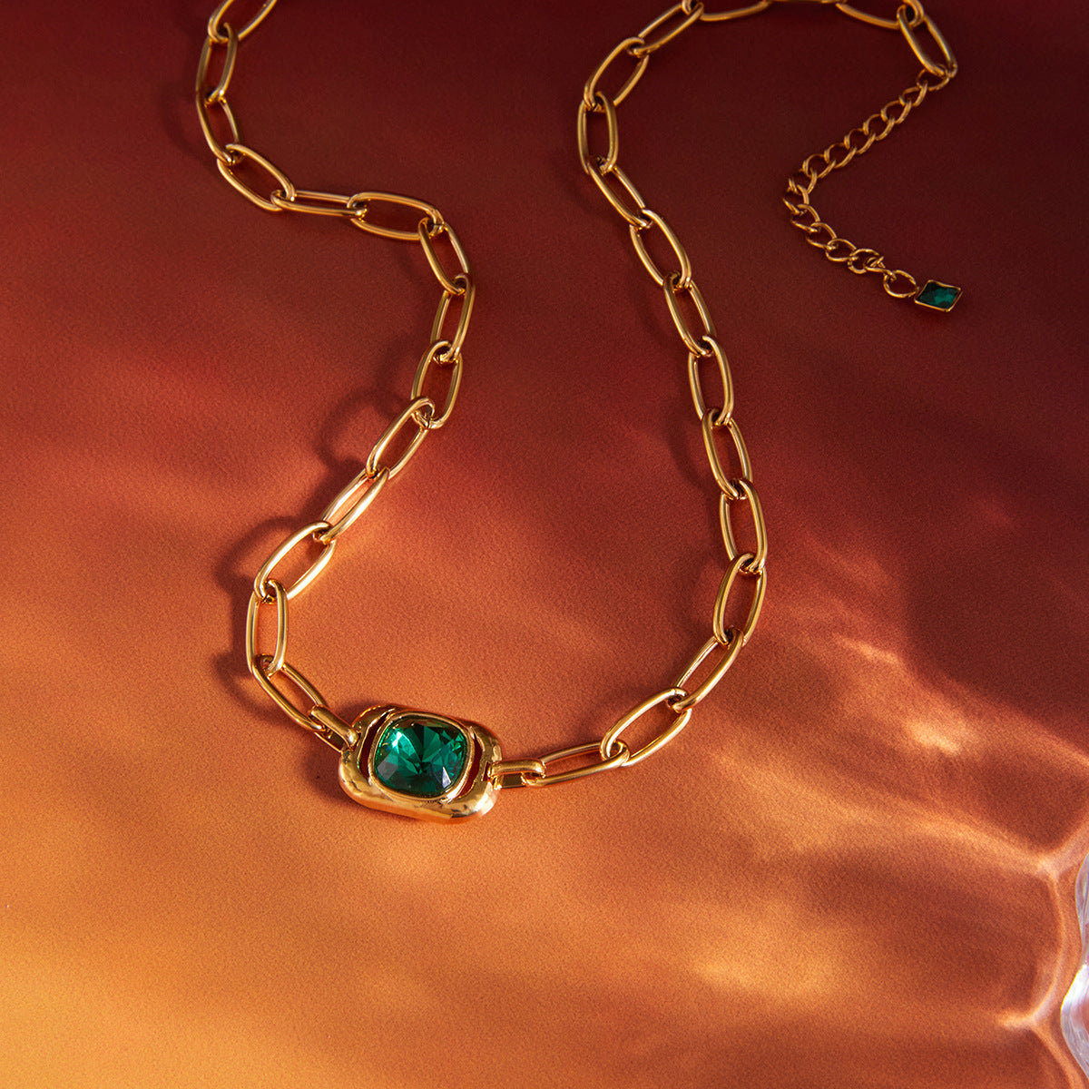 gold plated green glass necklace on warm reflective surface