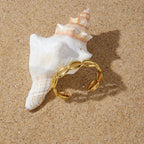 Gold tone shell motif cuff displayed on a spiral shell