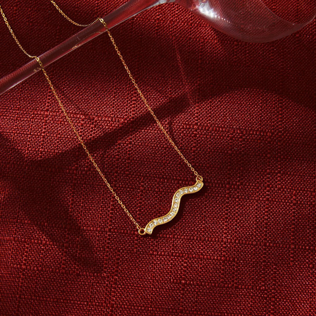 gold plated wave necklace styled on red fabric