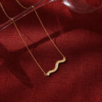 gold plated wave necklace styled on red fabric
