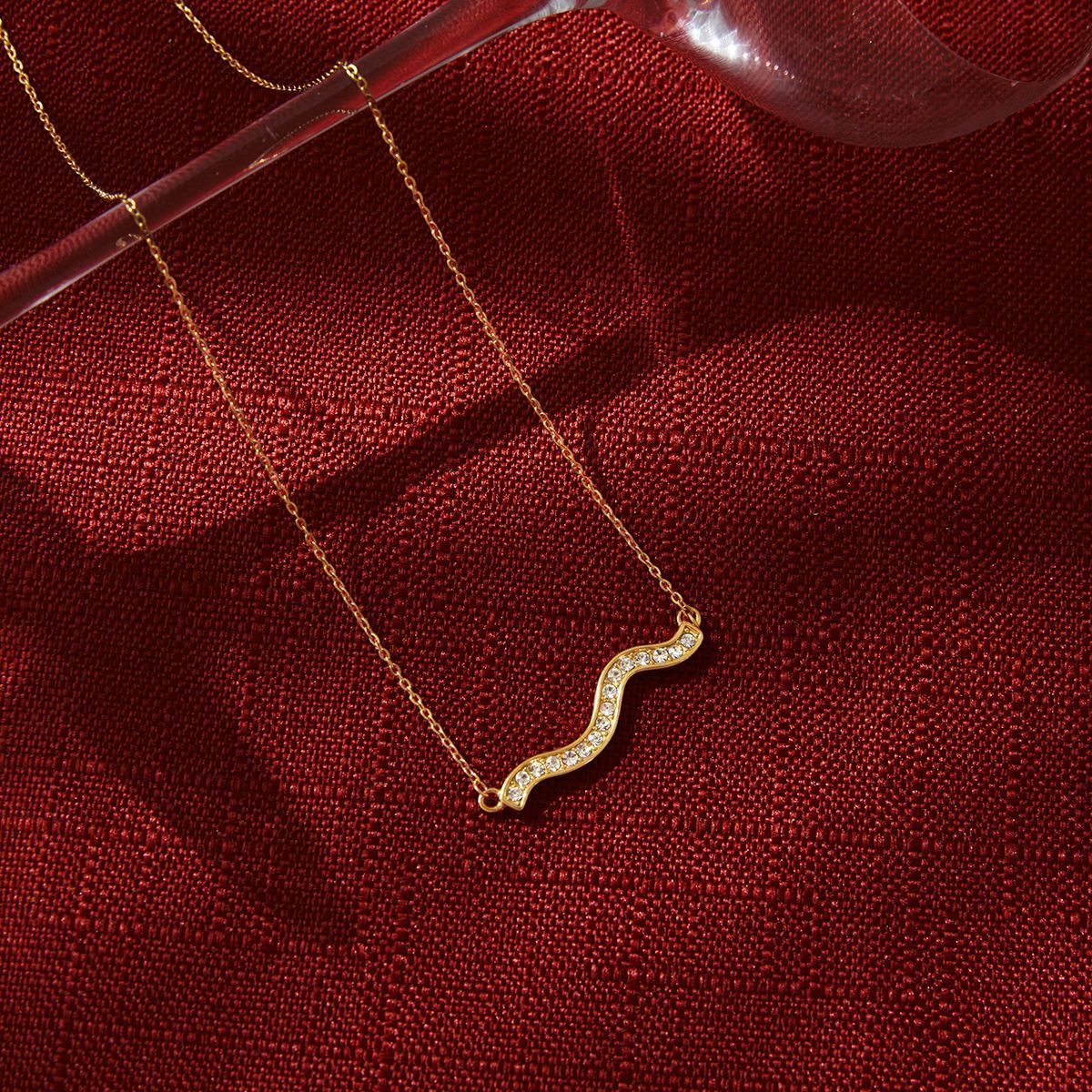 gold plated wave necklace styled on red fabric
