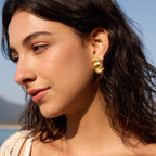 Gold-tone knot earring shown in side profile