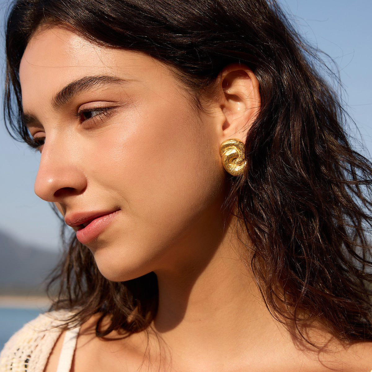 Gold-tone knot earring shown in side profile