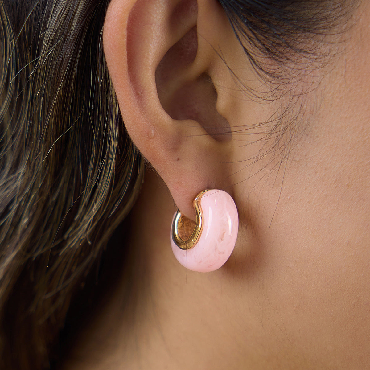 Pink faceted resin hoop with gold tone inner setting on the ear