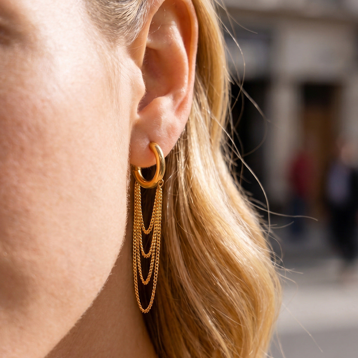 Draped chain hoop earring shown close-up on an ear