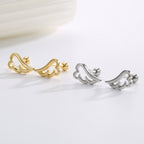 gold and silver angel wing stud earrings in a styled flat lay