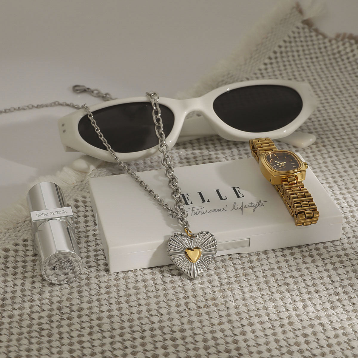 Silver-finish heart necklace displayed beside sunglasses