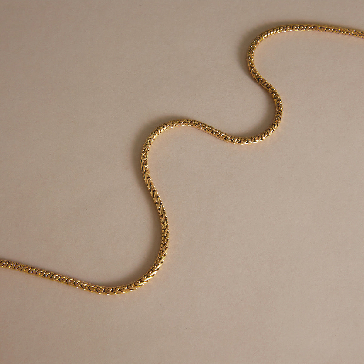 Close-linked necklace chain arranged in a soft curve