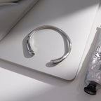 Silver-tone cuff with tapered rounded ends on a surface
