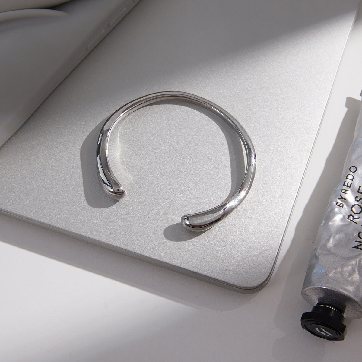 Silver-tone cuff with tapered rounded ends on a surface
