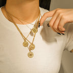 Several coin-style necklaces layered together on a model