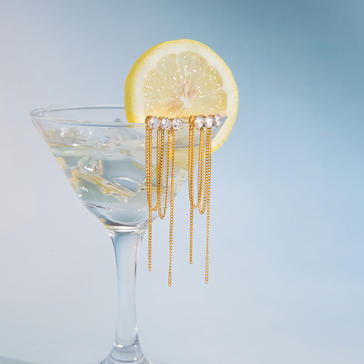 pair of clear-stone chain tassel earrings on a cocktail glass