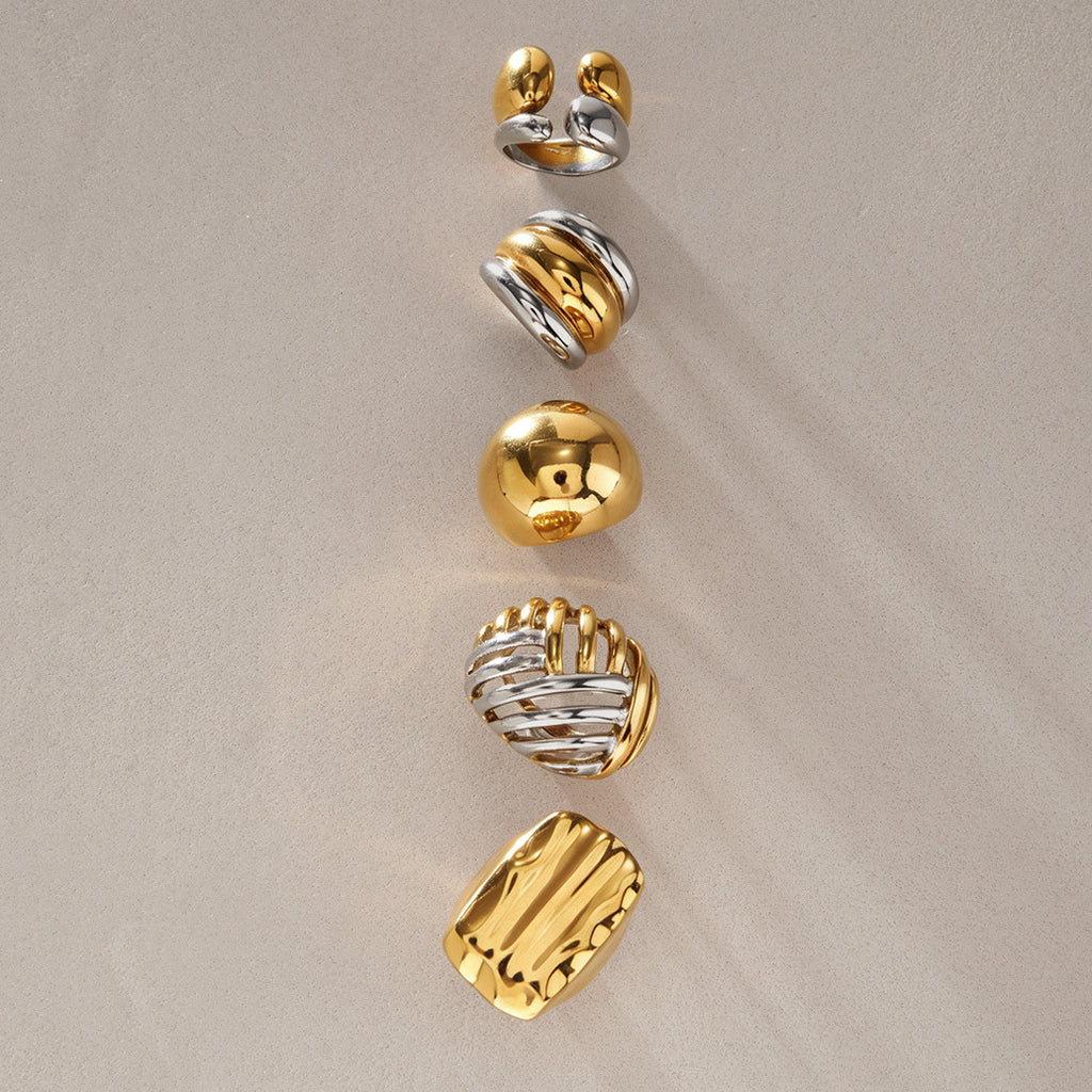 Five sculpted rings with gold and silver tone surfaces
