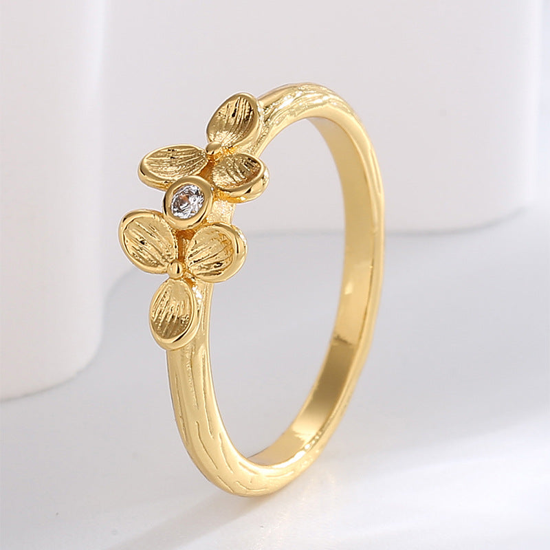 angled textured four-petal clover ring on pale display
