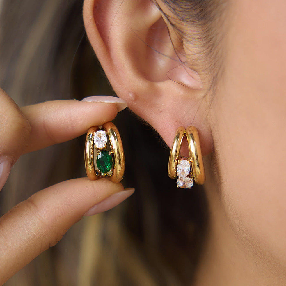 Clear and green double-curve earrings shown at the ear