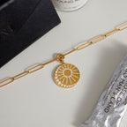 gold plated sunburst disc pendant necklace on a gray display surface