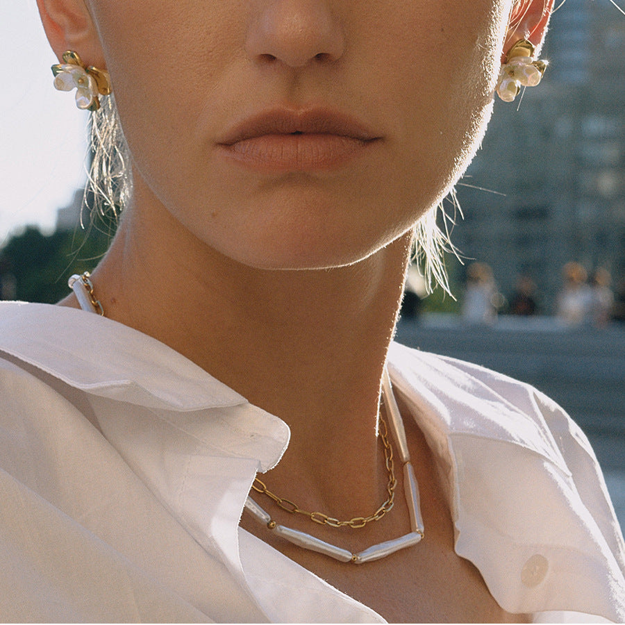 Layered gold plated chain and white bead necklaces on a model