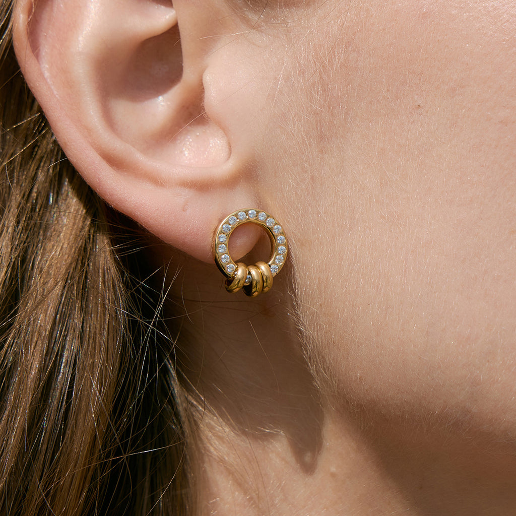 Circular stud with small ring accents worn close-up