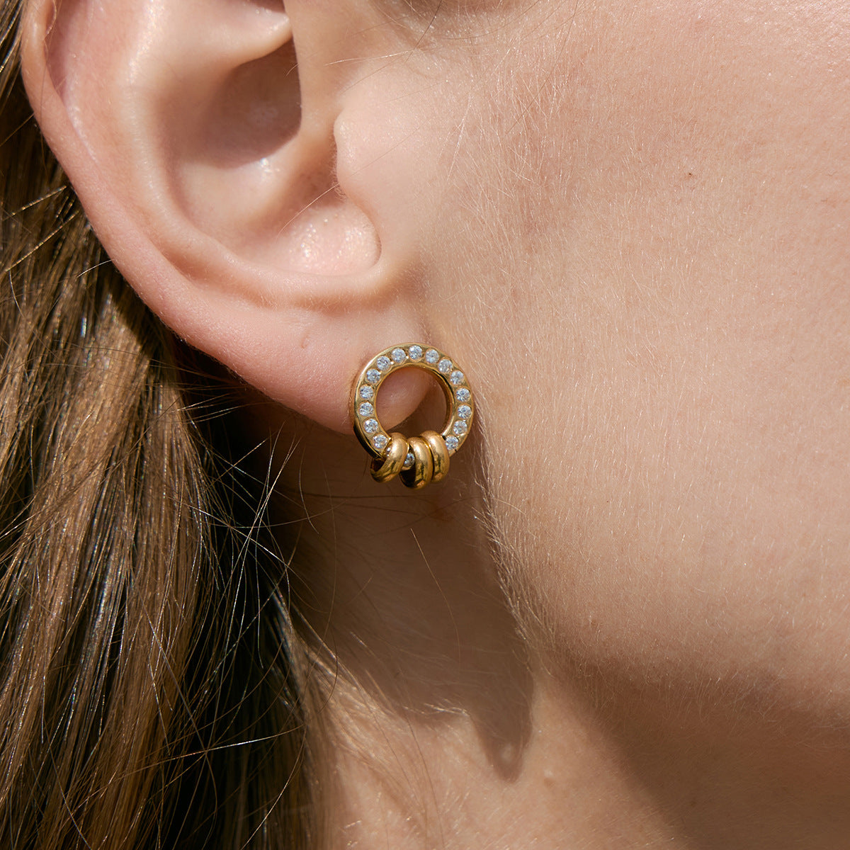 Circular stud with small ring accents worn close-up