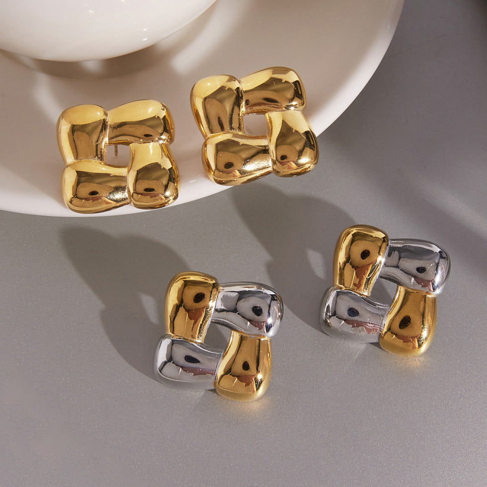 Gold and two tone woven square earrings beside a cup
