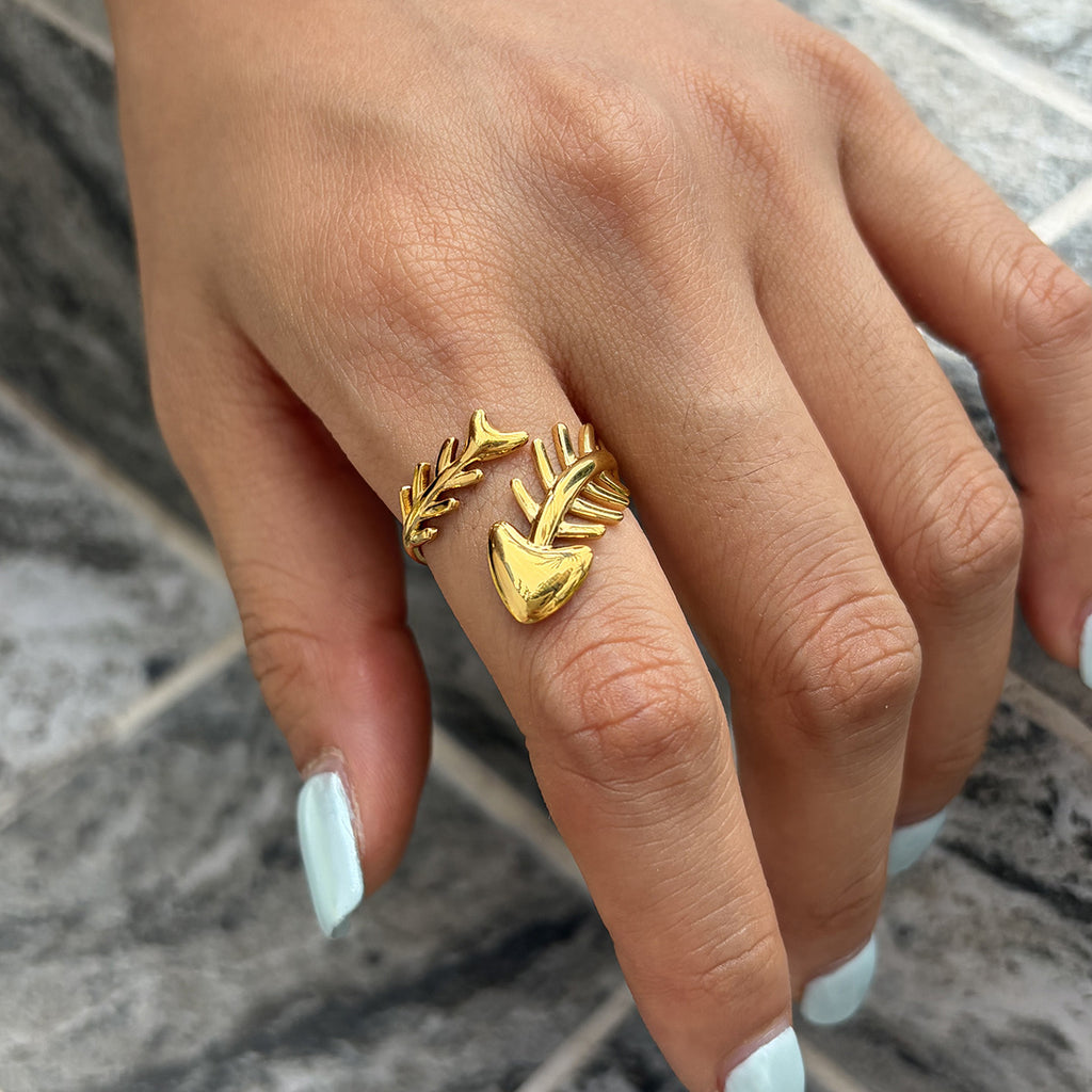 Gold-tone fish skeleton ring worn on a finger