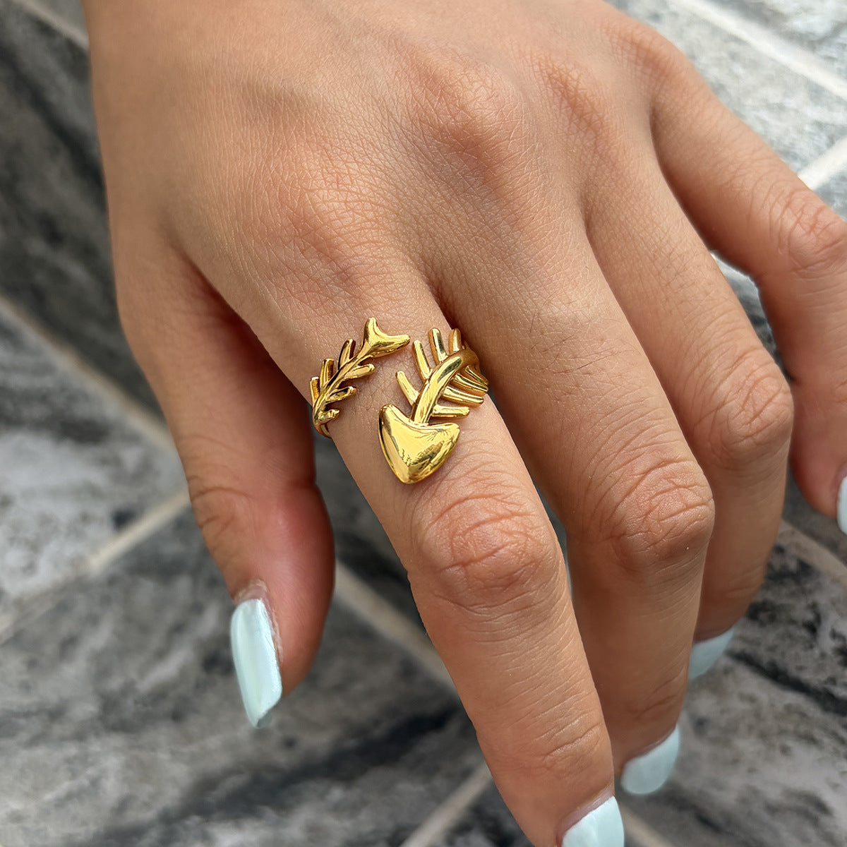 Gold-tone fish skeleton ring worn on a finger