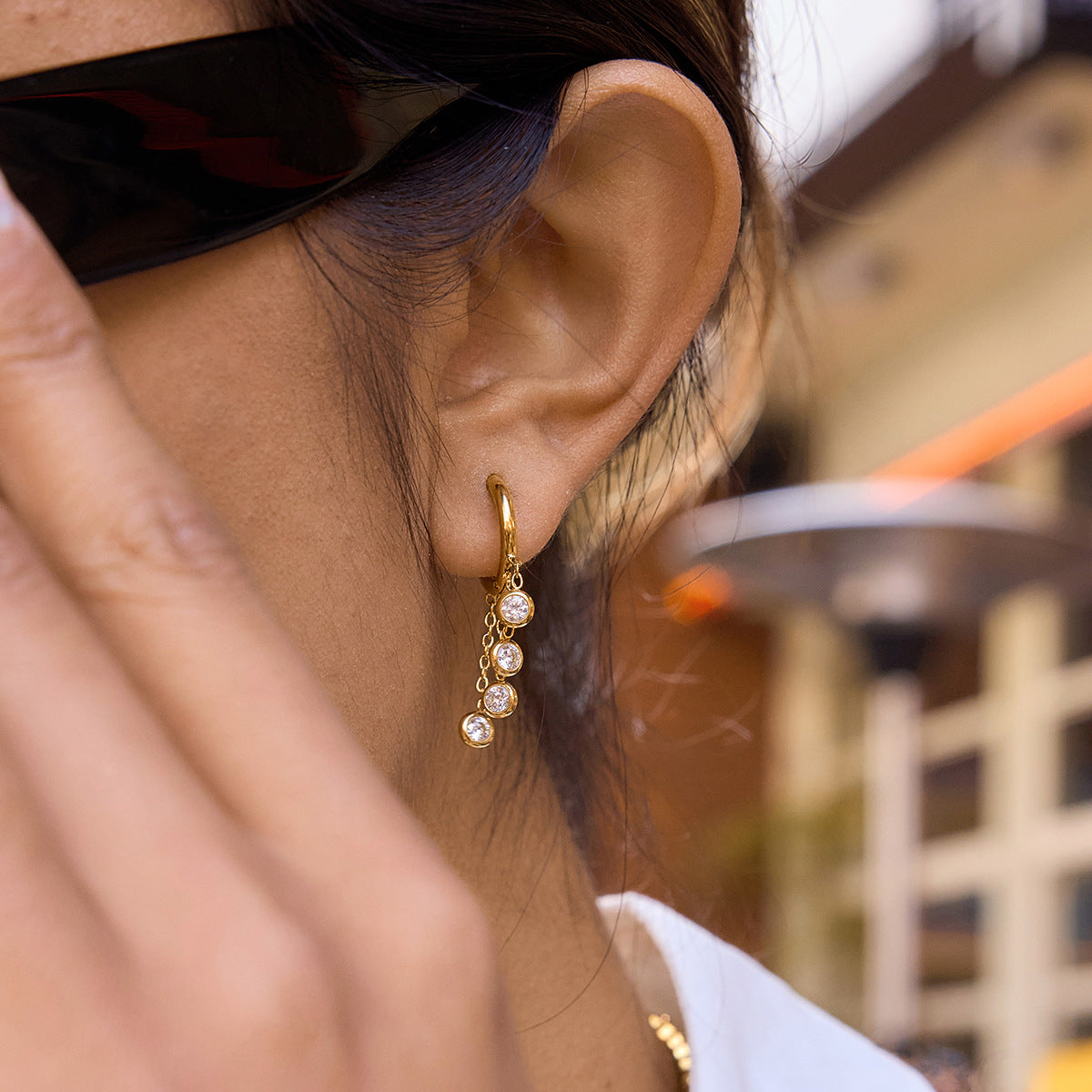 model wearing gold plated triple-stone chain drop hoop earrings