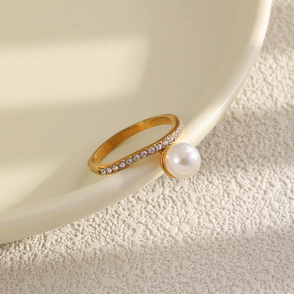 Ring showing offset pearl-look bead beside a white dish