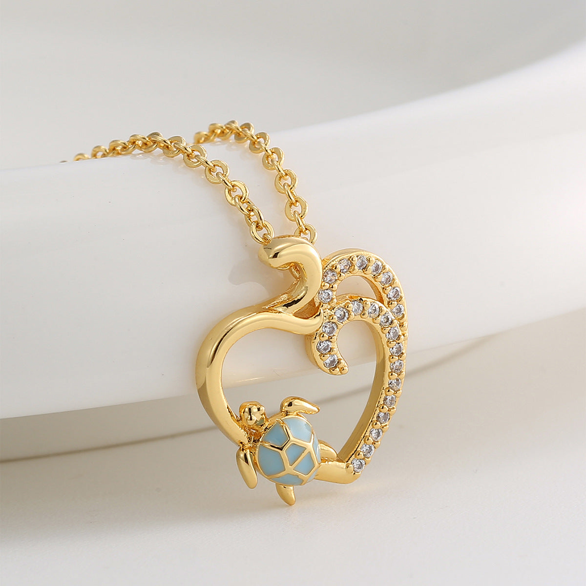 angled close view of blue resin turtle and open heart pendant