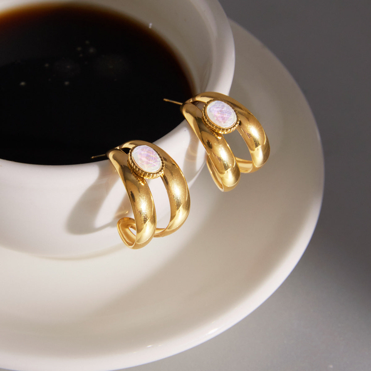 White inlay double hoop earrings beside a coffee cup