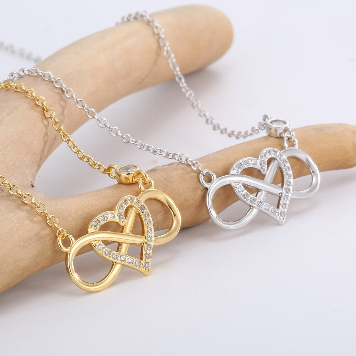 gold and silver finish infinity heart necklaces displayed across fingers